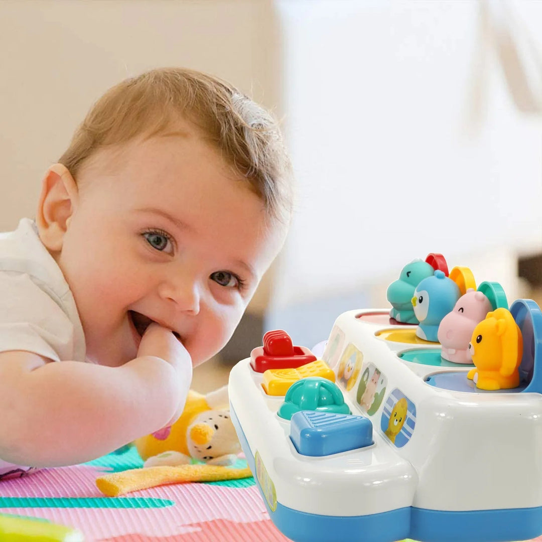 Baby lying beside the animal activity toy with four pop-up characters