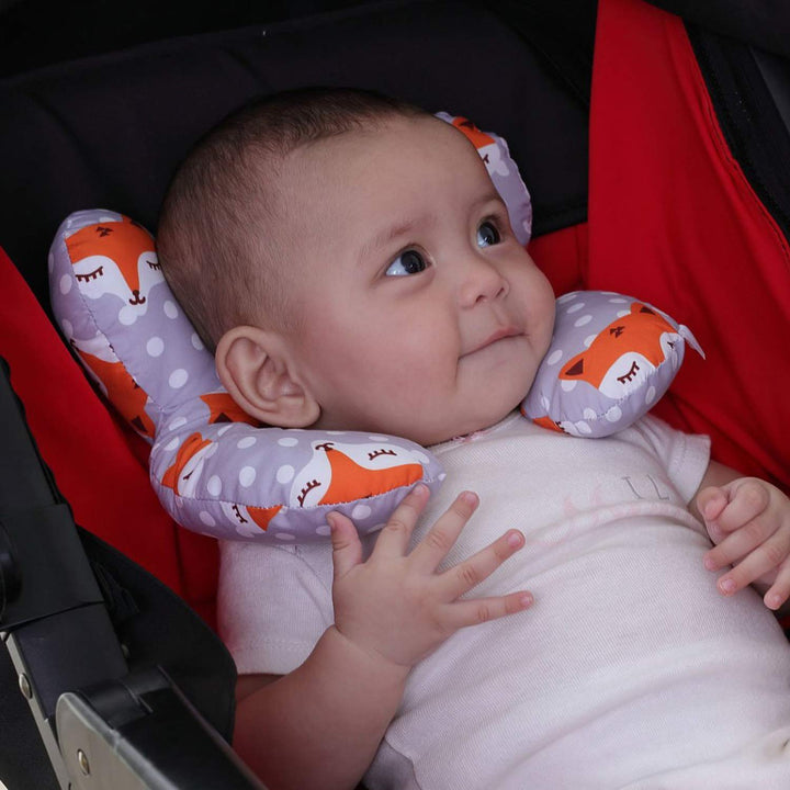 Baby reclining in a stroller with a gray fox-print contoured pillow around the neck