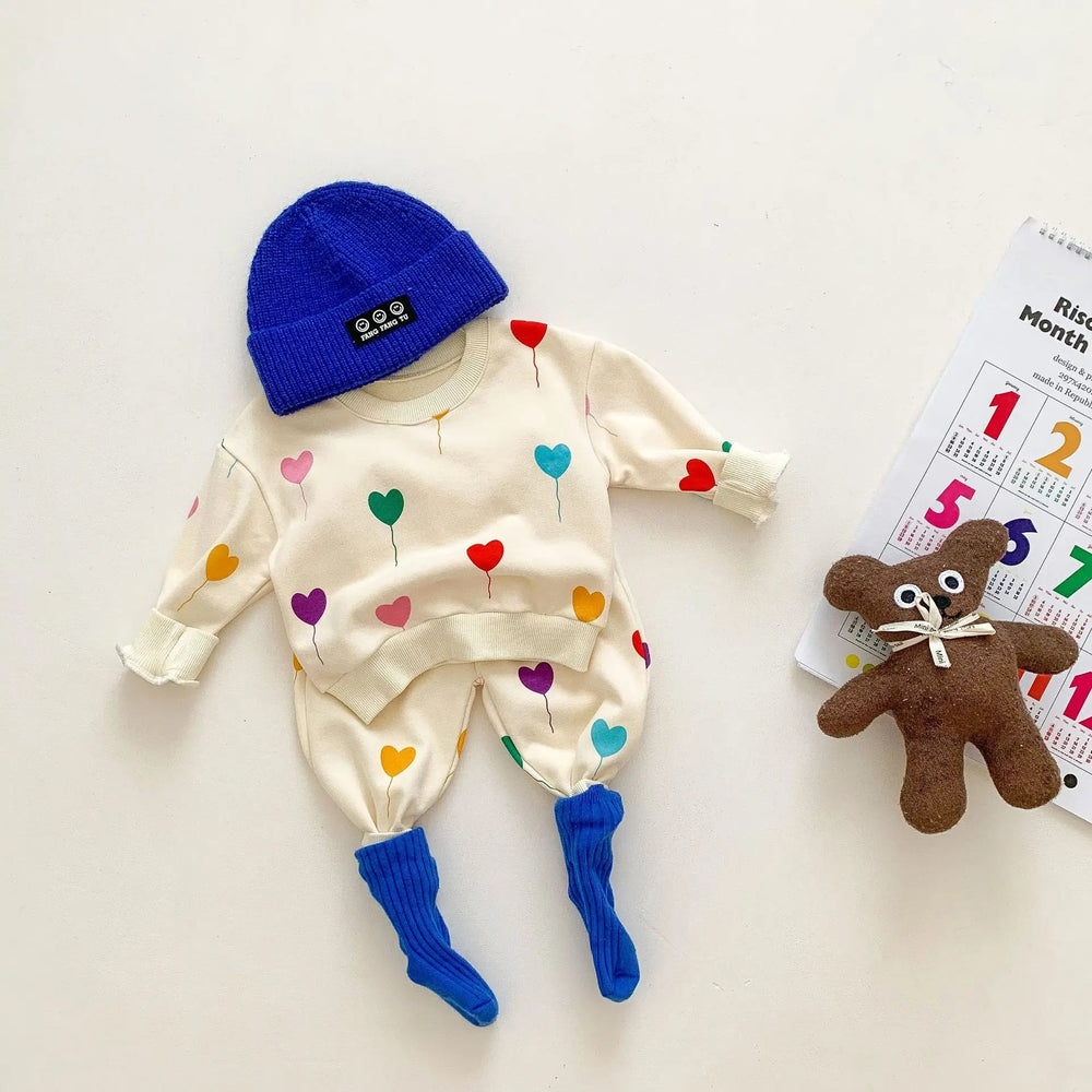 Heart-print baby sweater and pants styled with a blue knit hat and socks