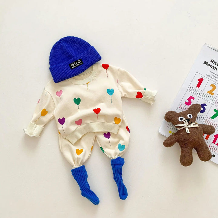 Heart-print baby sweater and pants styled with a blue knit hat and socks