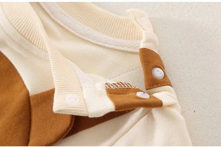 Opened shoulder snap fastenings beside the cream neckline of the baby jumpsuit