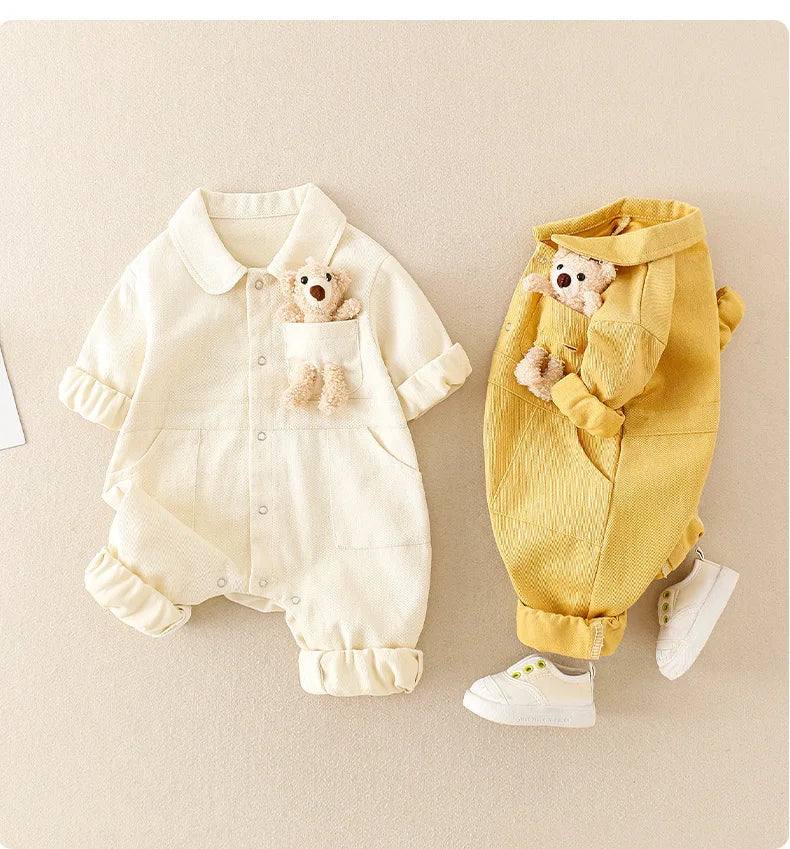 White and yellow baby jumpsuits with button fronts, rolled cuffs, and bear details.
