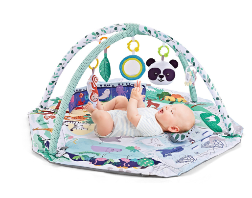 Baby lying on an animal-print play mat beneath green-and-white arches and hanging sensory toys