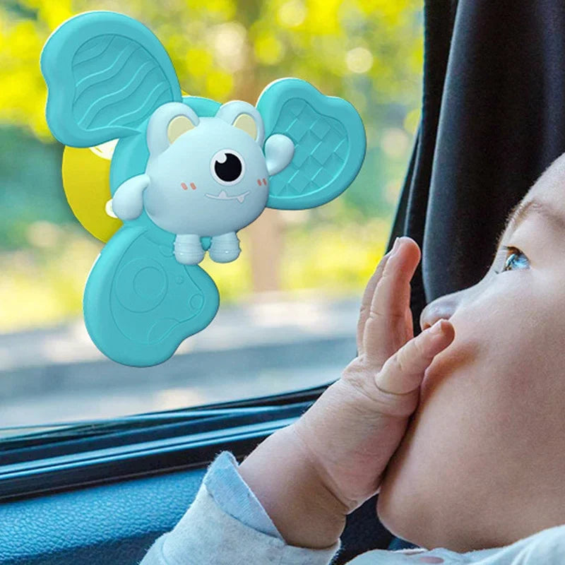 Baby reaching toward a mint animal spinner attached to a car window
