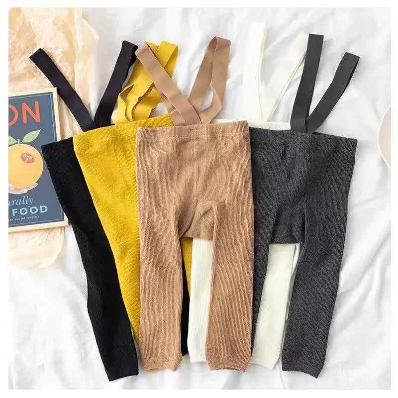 Black, yellow, light brown and dark gray baby leggings with suspenders laid flat