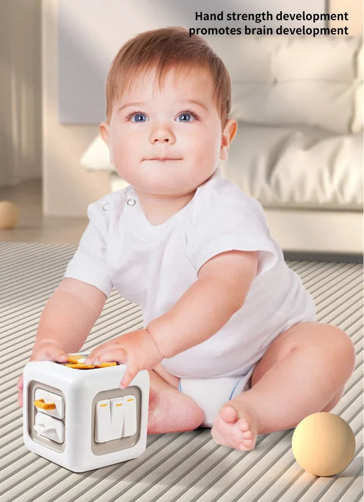 Baby sitting with a white and yellow sensory activity cube
