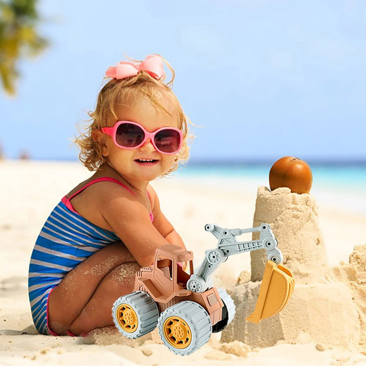 Child playing with a toy excavator beside a sandcastle on the beach