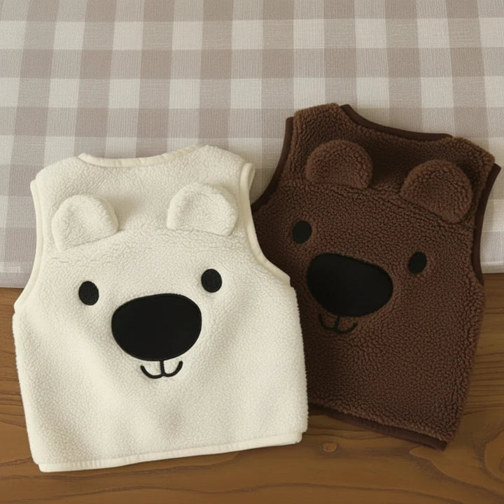 White and brown bear fleece vests with their bear-face backs facing up on a gingham surface.