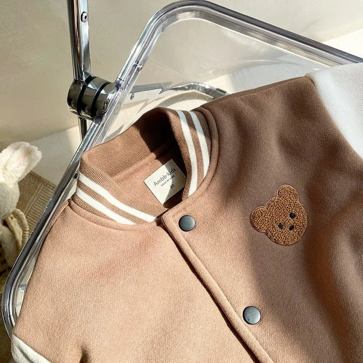 Close-up of the bear patch, snap fastening and striped collar on the brown jacket
