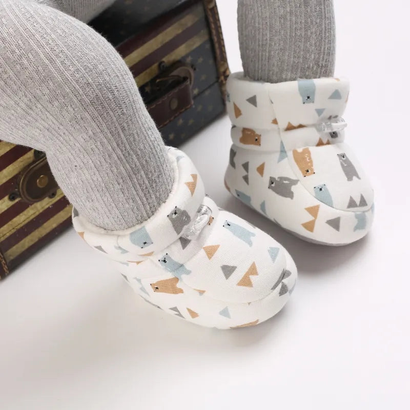 Bear-print baby slippers worn with gray leggings, showing ankle-height cuffs