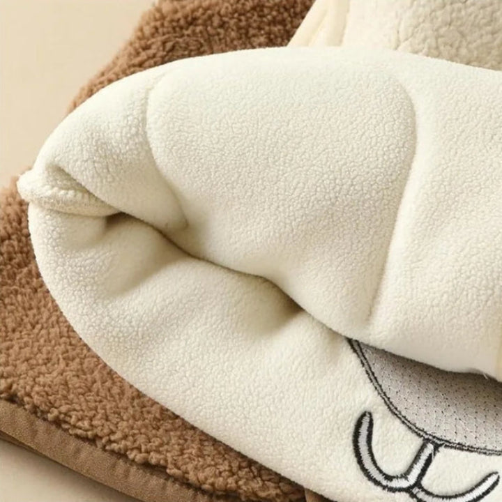 Folded white fleece lining over a brown vest, with part of the bear design visible.