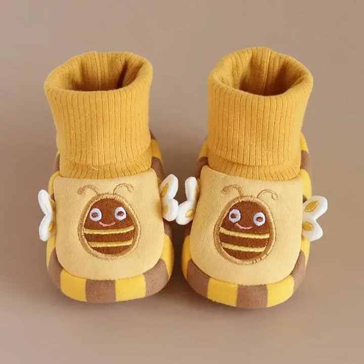 Pair of yellow bee indoor shoes with tall ribbed cuffs on a beige surface
