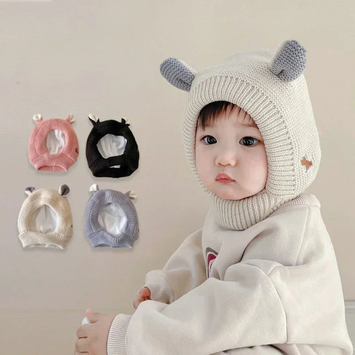 Baby wearing a beige balaclava with gray ears beside pink, black, beige, and gray color options
