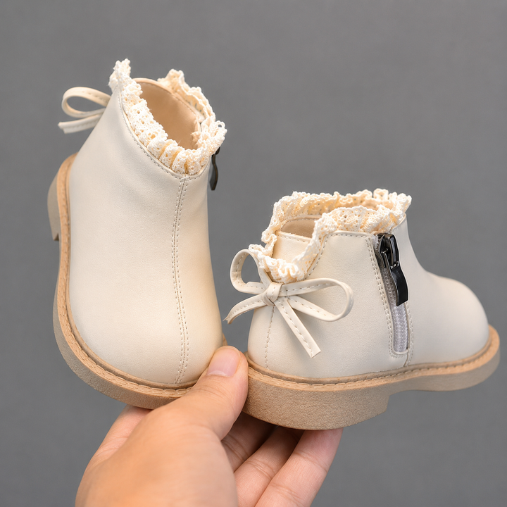 Beige ankle boots showing side zippers, back bows, and light-colored soles