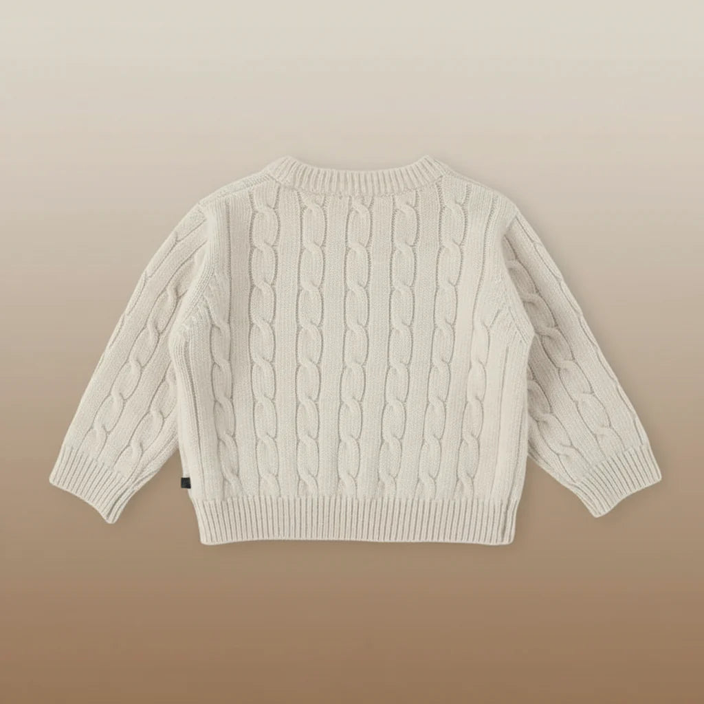 Beige long-sleeve cable-knit sweater laid flat with ribbed cuffs and hem