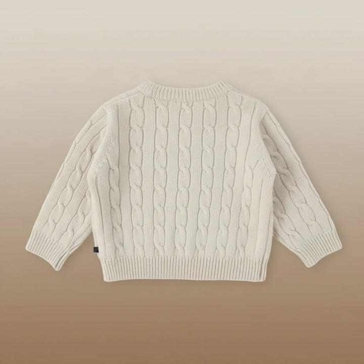 Beige long-sleeve cable-knit sweater laid flat with ribbed cuffs and hem