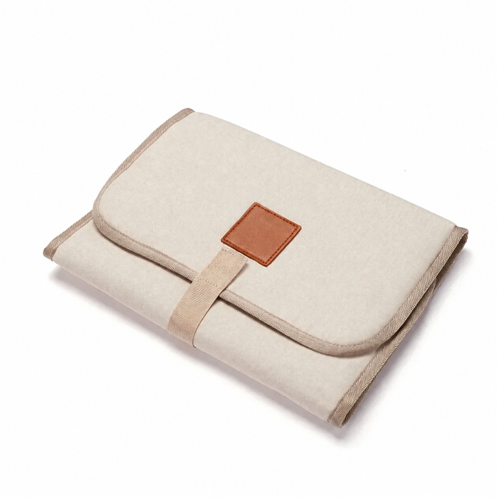 Beige baby changing mat folded with a rounded flap and front closure strap