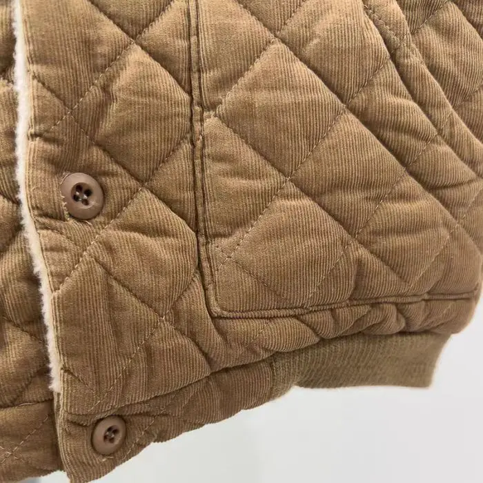 Close-up of diamond quilting, a front pocket, and buttons on the beige coat