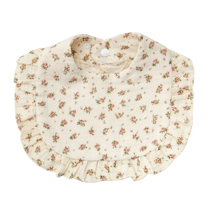 Beige cotton baby bib with small floral sprigs, ruffled trim, and neck snaps