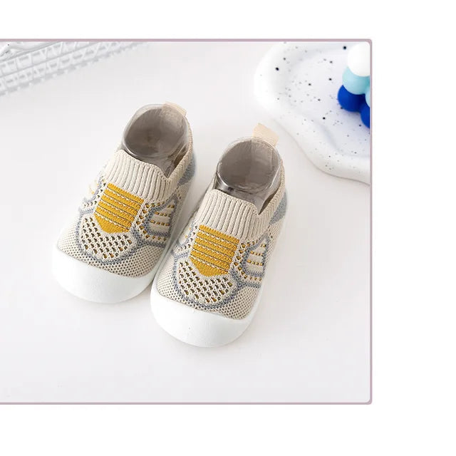 Pair of beige knit slip-on shoes with yellow accents and white soles