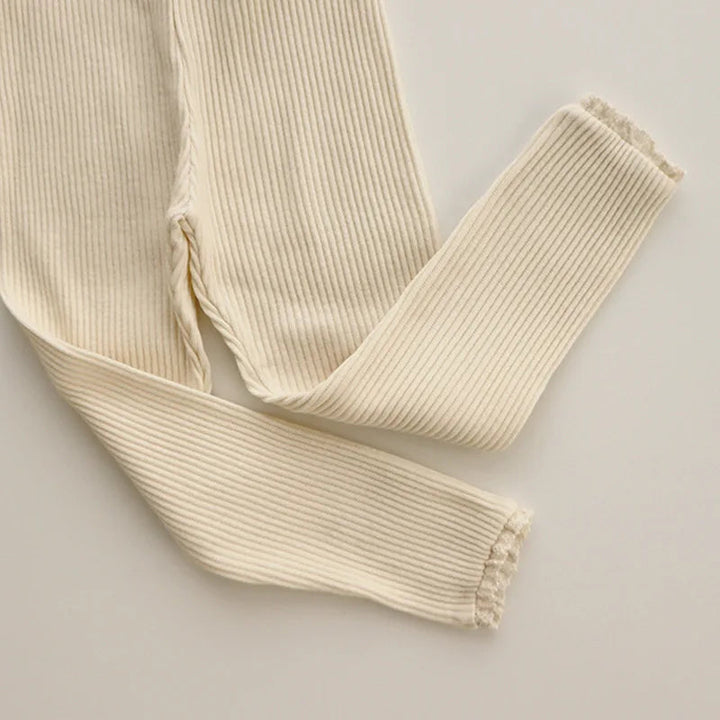 Beige cotton leggings showing fine ribbing and lace detail at the ankle openings.