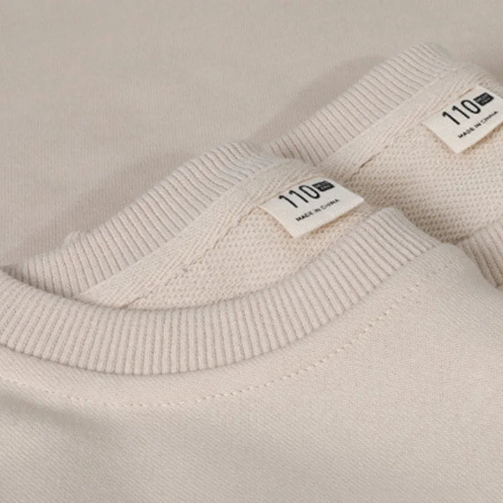 Close-up of ribbed crew necks on beige cotton Christmas sweaters