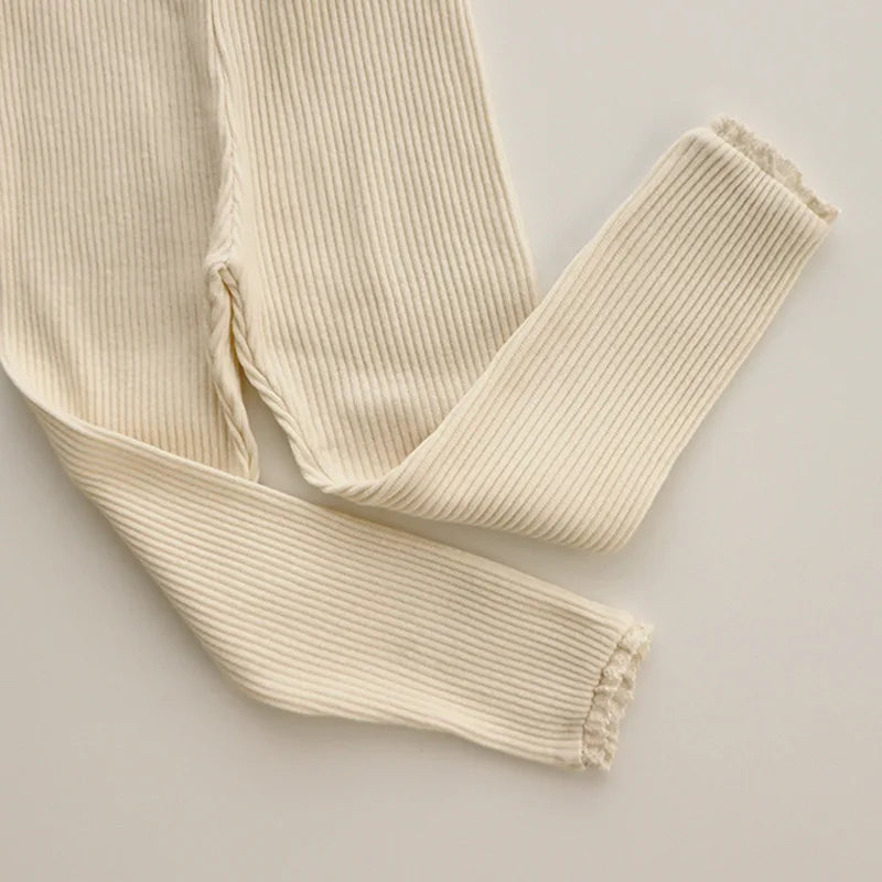 Beige ribbed leggings laid flat with crossed legs and lace-trimmed ankles.
