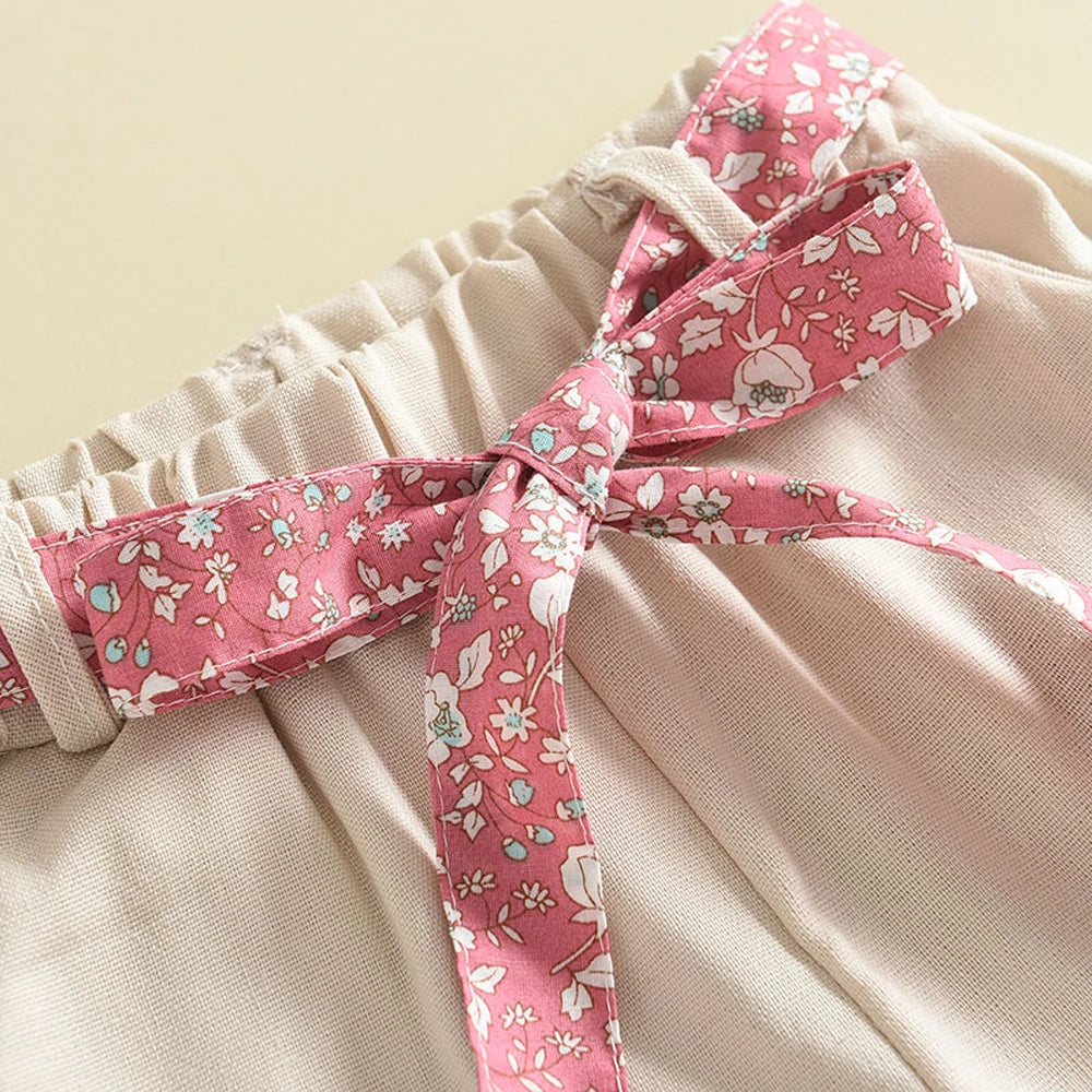 Gathered waistband on beige shorts with a pink floral bow tie