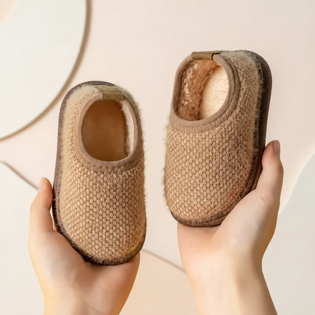 Beige textured winter slippers with cream trim and brown soles, held in two hands