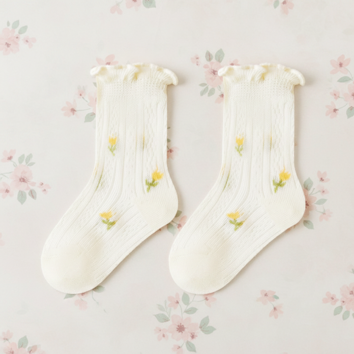 Pair of beige baby socks with tiny flowers, pointelle knit, and ruffled cuffs.