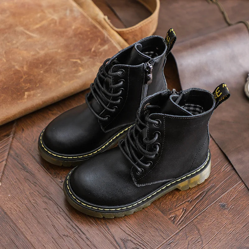 Black ankle lace-up boots with side zippers and translucent soles on a wooden floor