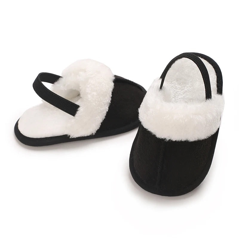 Black baby slippers showing white plush trim, lining and heel straps