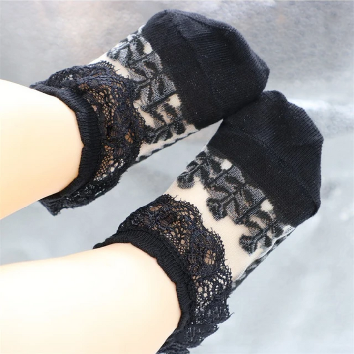 Black baby socks with sheer floral lace panels and decorative ankle trim.