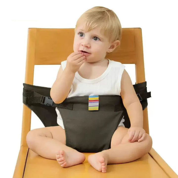 Black baby chair harness wrapped around a child and a wooden chair back.