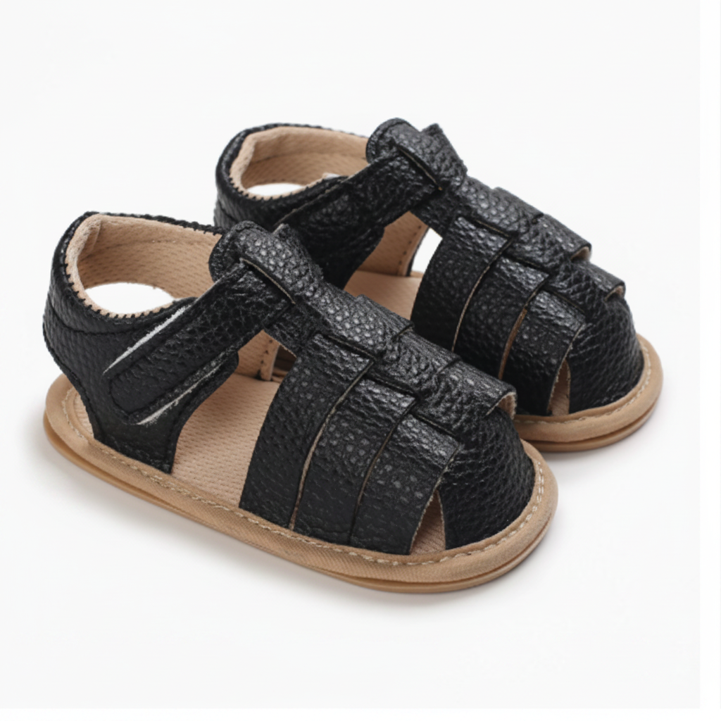 Pair of black closed-toe baby sandals with interwoven straps and ankle fastenings