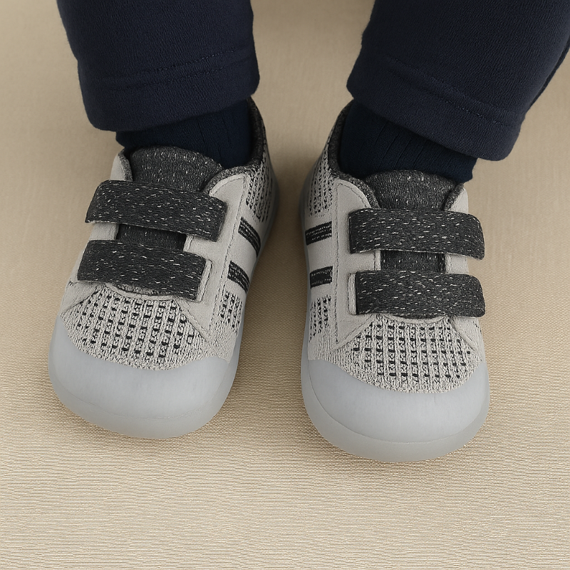 Black-gray mesh baby shoes with double straps worn with dark pants