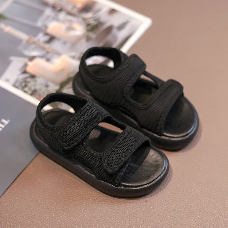 Black kids' sandals with open toes, heel straps, and hook-and-loop closures