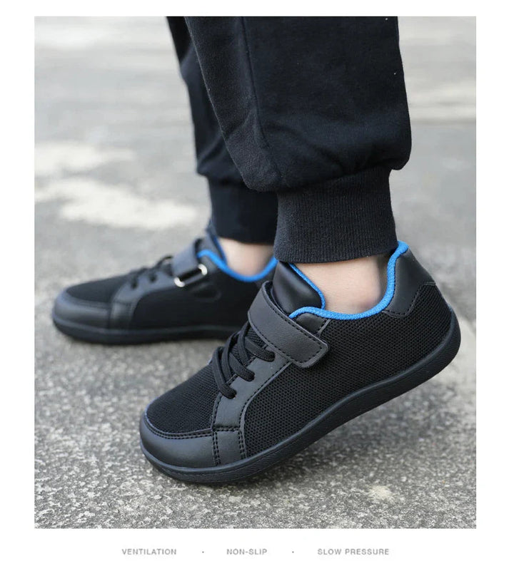 Side view of black low-top sneakers with blue lining worn on pavement