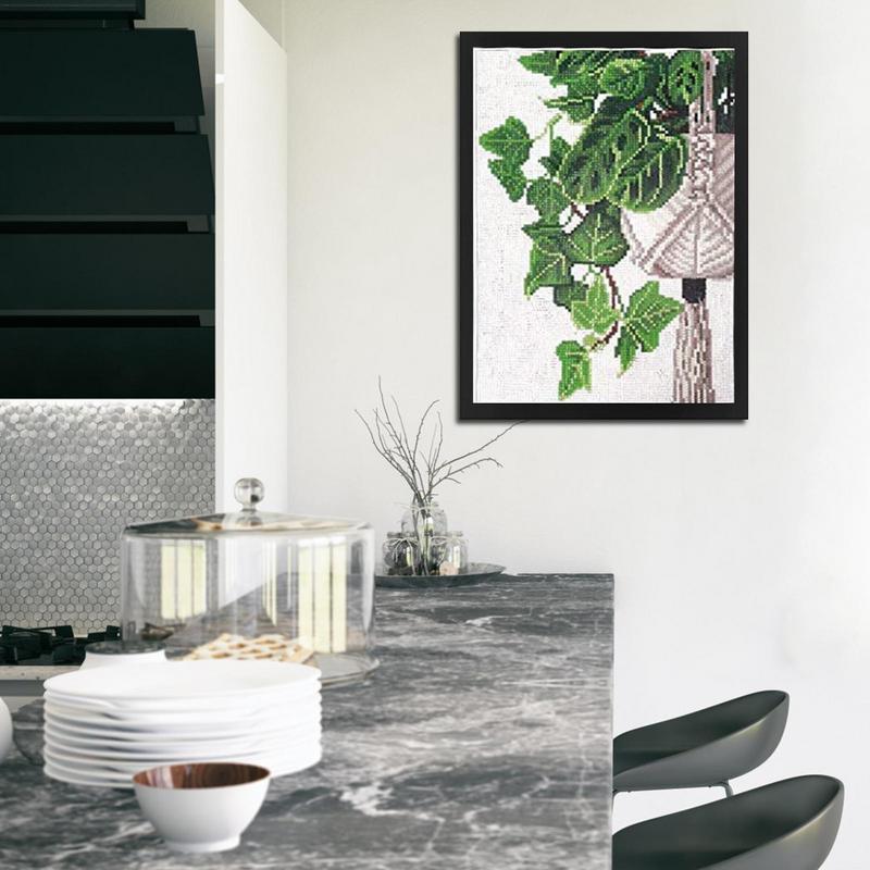 Black magnetic picture frame displaying a green botanical print above a kitchen counter