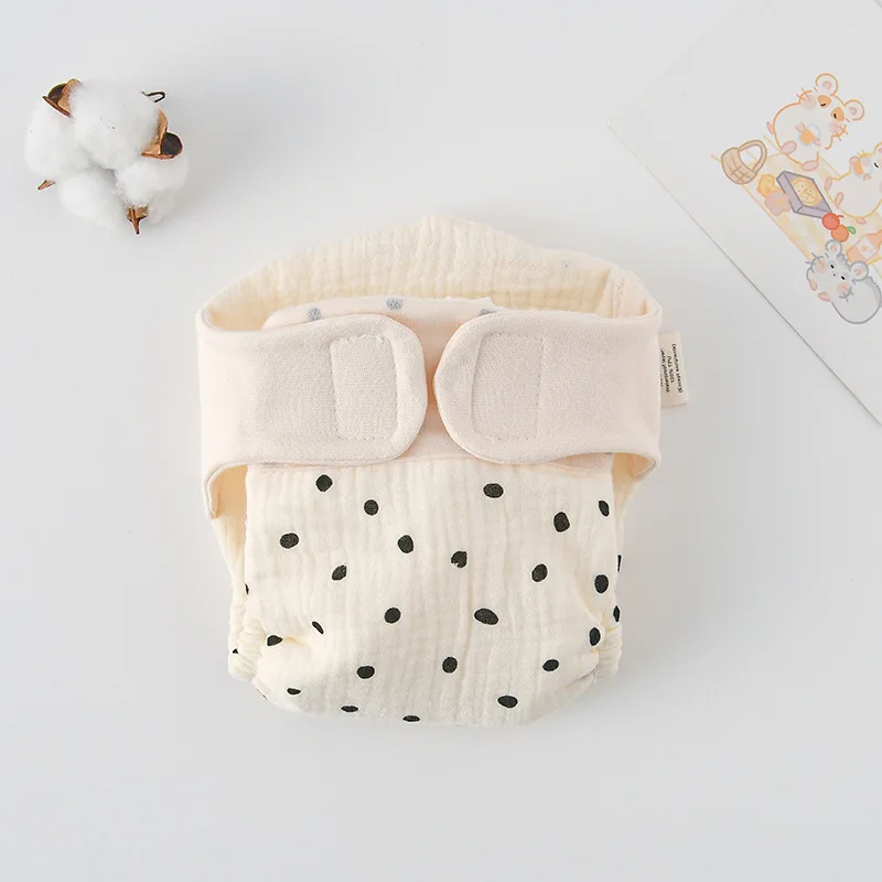 Cloth diaper with small black polka dots and a cream hook-and-loop waistband