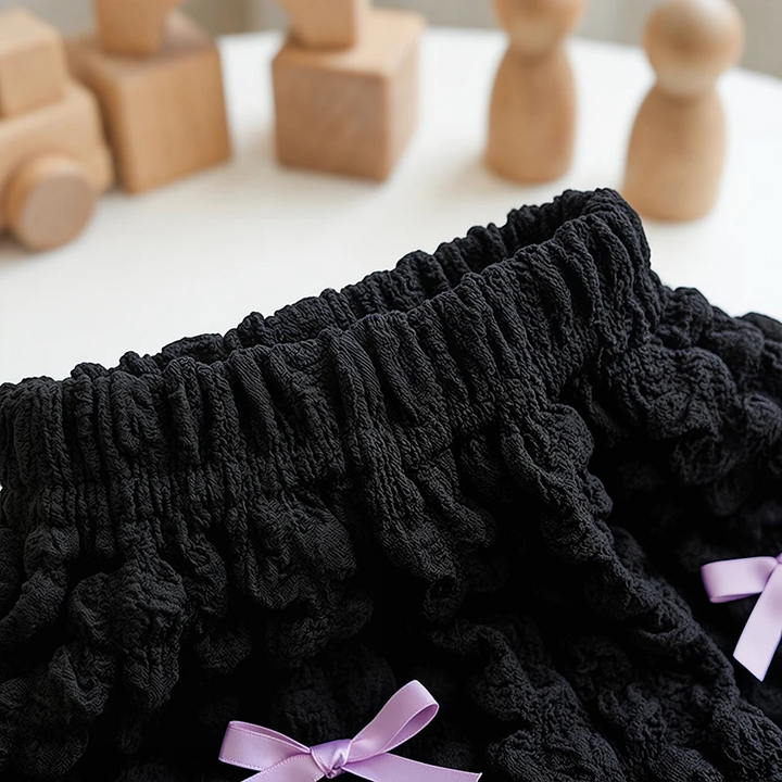 Close-up of the gathered elastic waistband on black ruffle shorts