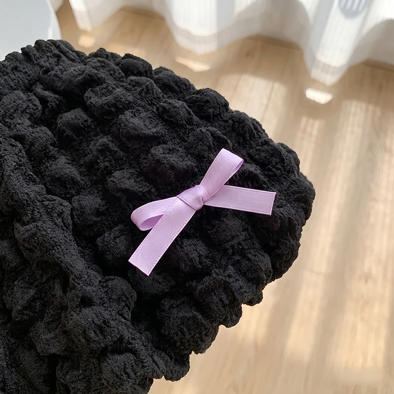 Lavender ribbon bow detail on textured black ruffle shorts