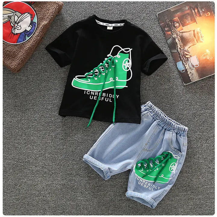 Black short-sleeve T-shirt and blue denim shorts with matching green sneaker graphics, laid flat