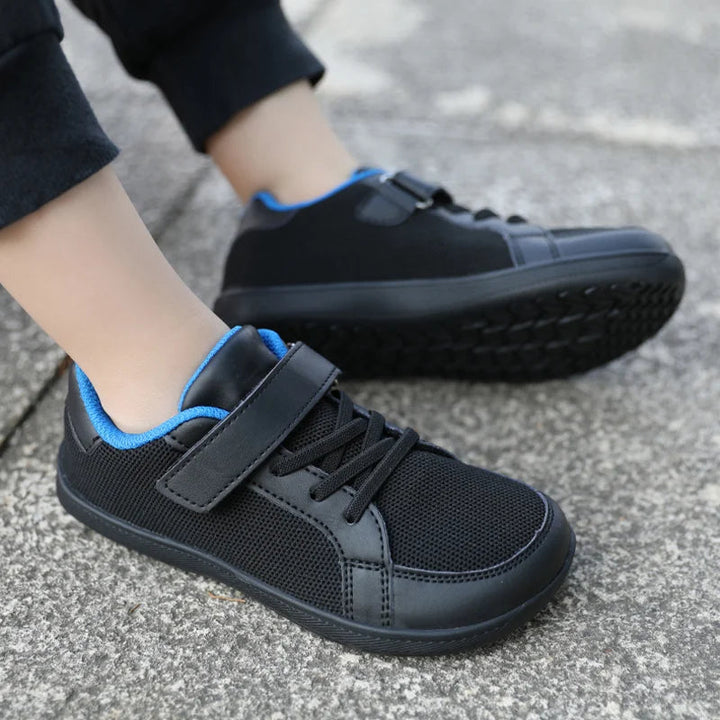 Black sneakers worn on pavement, showing blue lining and the underside of one sole