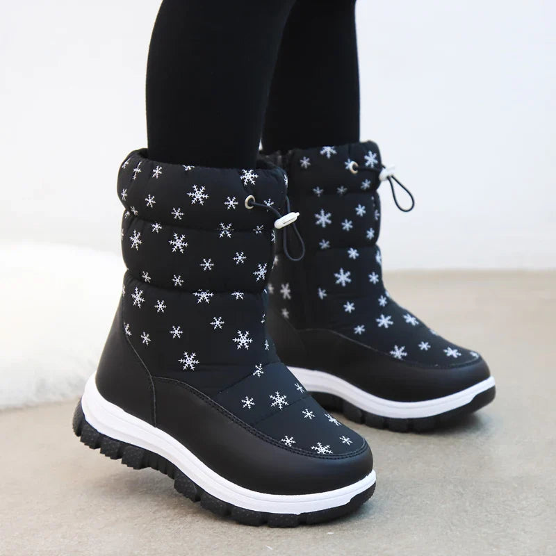 Black snowflake-print snow boots worn with leggings, with drawcord cuffs and white midsoles