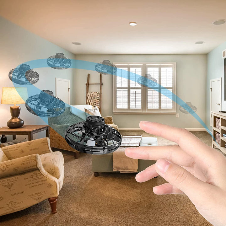 Hand guiding a black UFO drone along an illustrated flight path in a living room