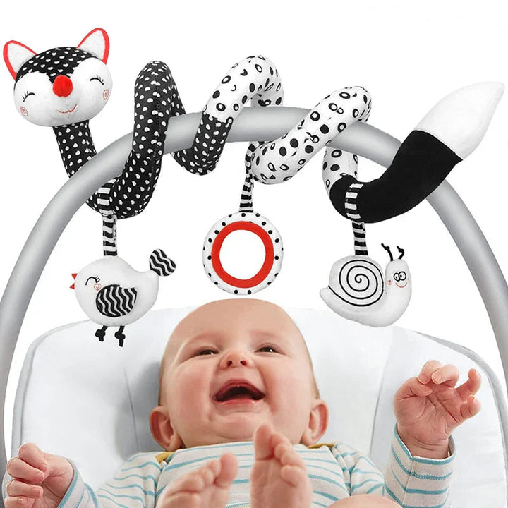 Baby beneath a black-and-white fox spiral activity toy wrapped around a seat handle.