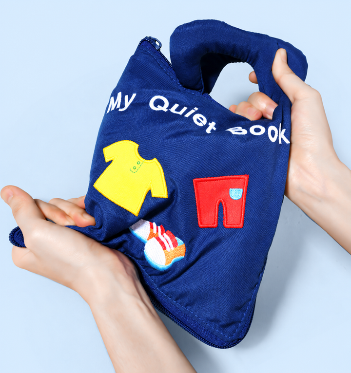 Soft blue activity book held by its handle, with colorful clothing shapes on the cover