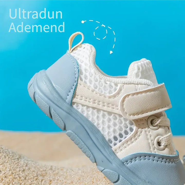 Side detail of a blue baby shoe showing open mesh panels, a white strap and a heel pull tab