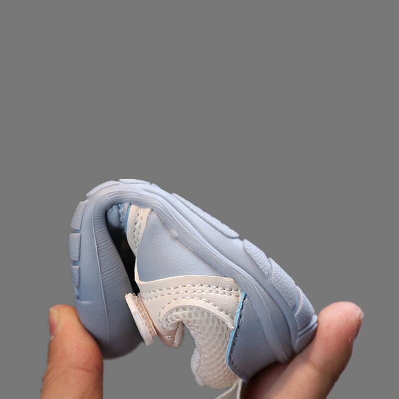 A blue baby sneaker bent by hand to show the flexibility of its sole